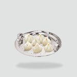 Load image into Gallery viewer, Seven steamed modak dumplings with saffron on a round stainless steel perforated plate
