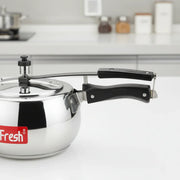 Stainless steel pressure cooker with black handle on white kitchen countertop