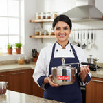 Load image into Gallery viewer, Smiling chef in blue apron holding Max Fresh stainless steel pressure cooker in modern kitchen