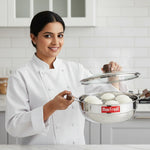 Load image into Gallery viewer, Smiling female chef holding a stainless steel Max Fresh idli steamer with wooden handles in modern kitchen