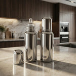 Load image into Gallery viewer, Two shiny stainless steel baby feeding bottles on marble kitchen countertop with dark wood cabinets