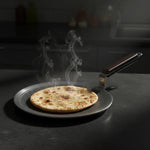 Load image into Gallery viewer, Hot flatbread cooking on a MaxFresh non-stick round roti pan with steam rising on a dark countertop