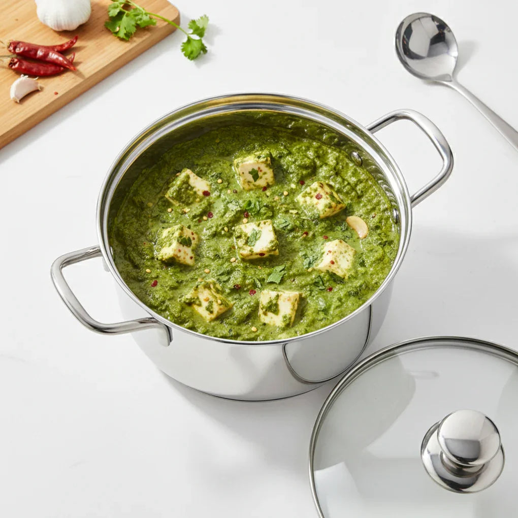 Stainless steel casserole pot with paneer spinach curry on a white kitchen counter