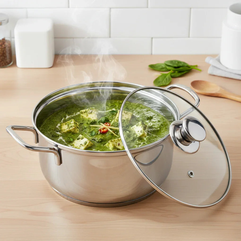 Stainless steel casserole pot with glass lid, steaming spinach paneer curry on kitchen counter
