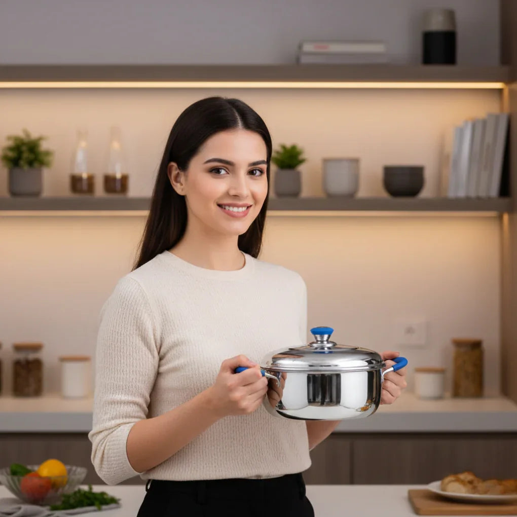 Smiling woman holding stainless steel pot with blue handles in modern kitchen setting