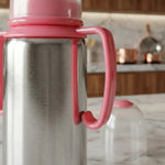 Load image into Gallery viewer, Close-up of stainless steel thermos with pink plastic handle and lid on marble kitchen counter