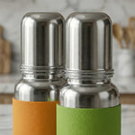 Load image into Gallery viewer, Close-up of two stainless steel water bottles with orange and green textured sleeves on kitchen counter