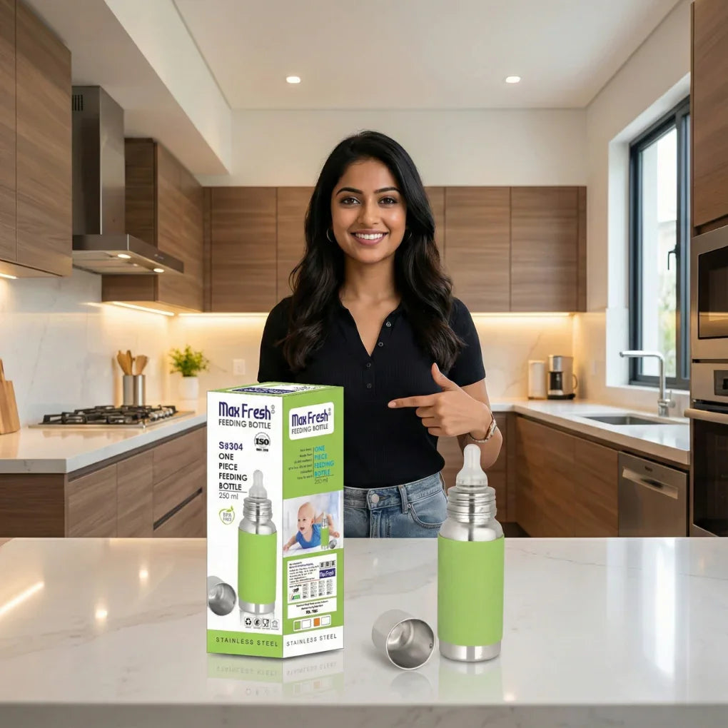 Smiling woman in modern kitchen pointing at Max Fresh stainless steel baby feeding bottle with green cover