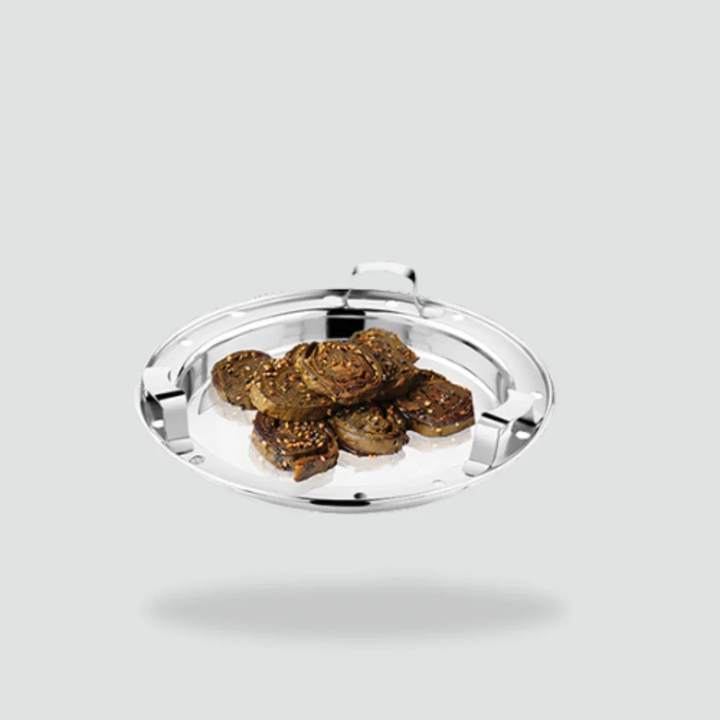 Stainless steel steamer plate with savory Indian snacks on a light background