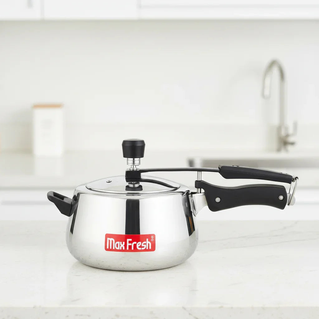 Stainless steel pressure cooker with black handles on a kitchen countertop