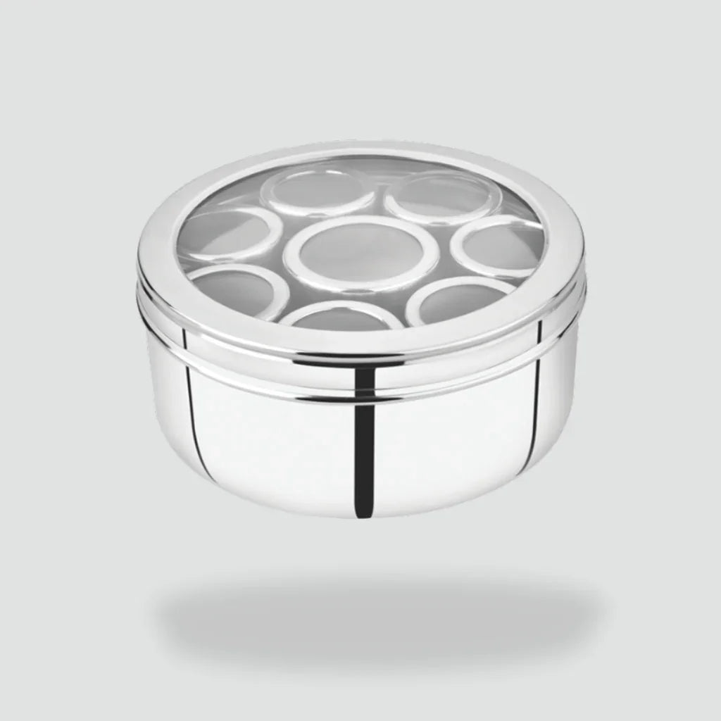 Stainless steel multi kadai with glass lid and seven round containers on a grey background