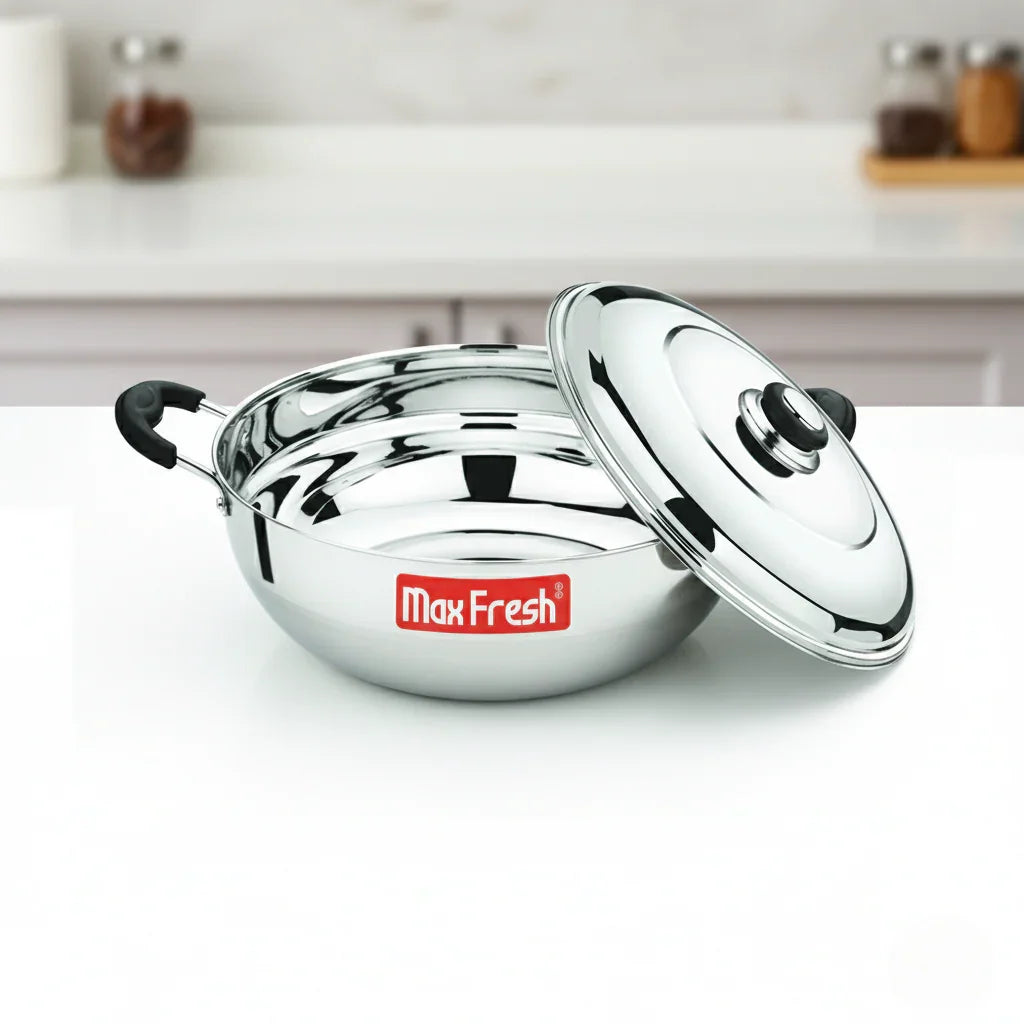 Stainless steel multi kadai with lid and black handles on a kitchen counter