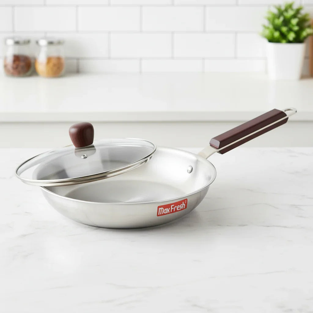 Stainless steel frypan with glass lid and wooden handle on kitchen counter
