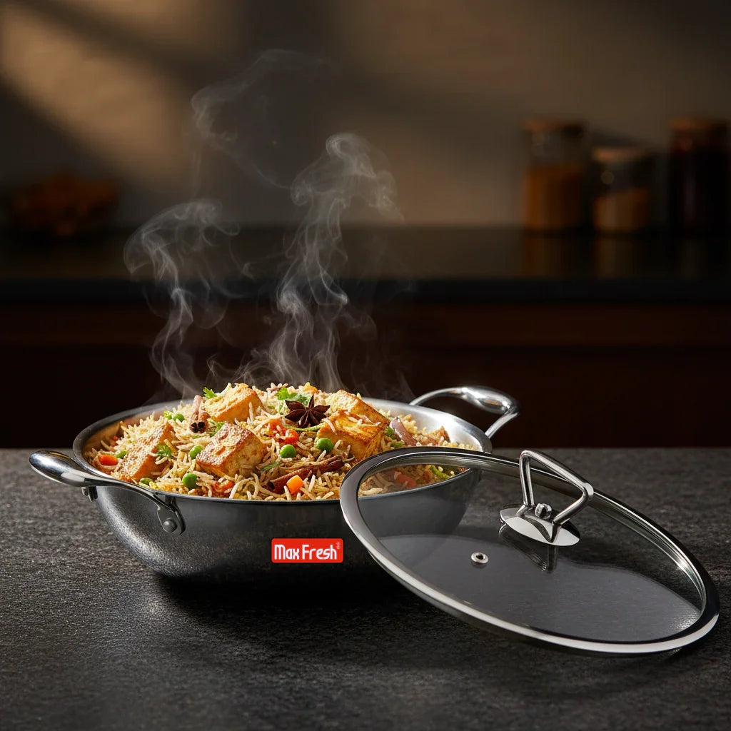 Stainless steel kadai with steamy biryani and glass lid on kitchen counter
