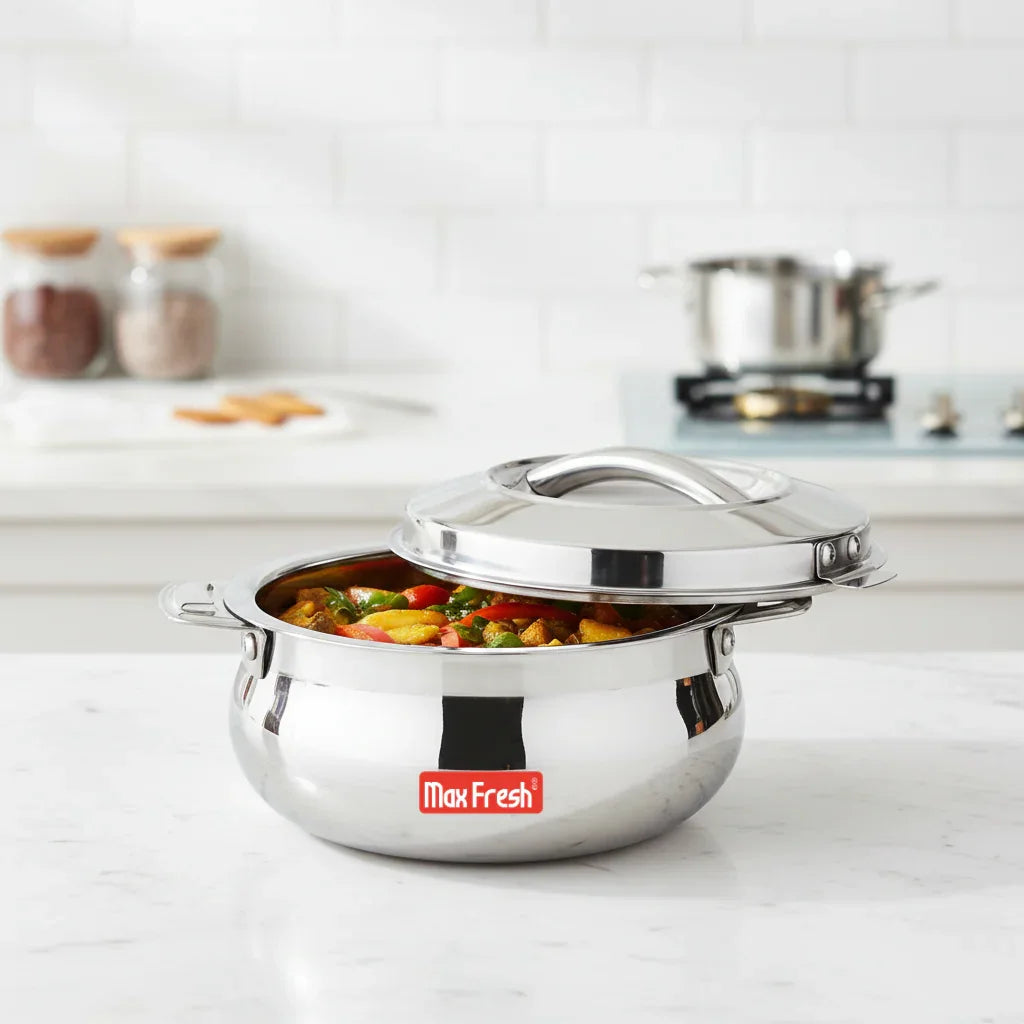 Stainless steel casserole dish with lid, filled with cooked vegetables on a kitchen counter
