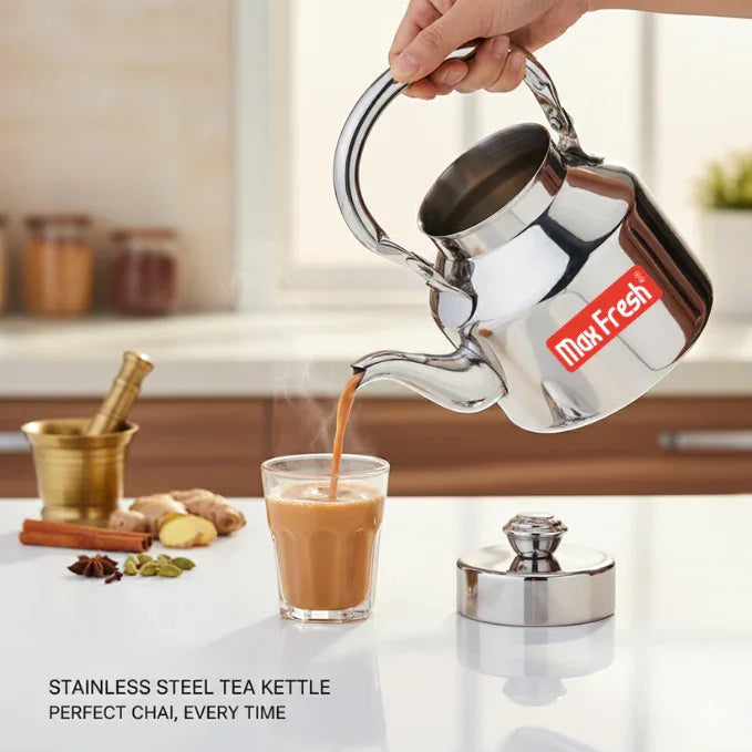 Stainless steel tea kettle pouring hot chai into glass in modern kitchen setting