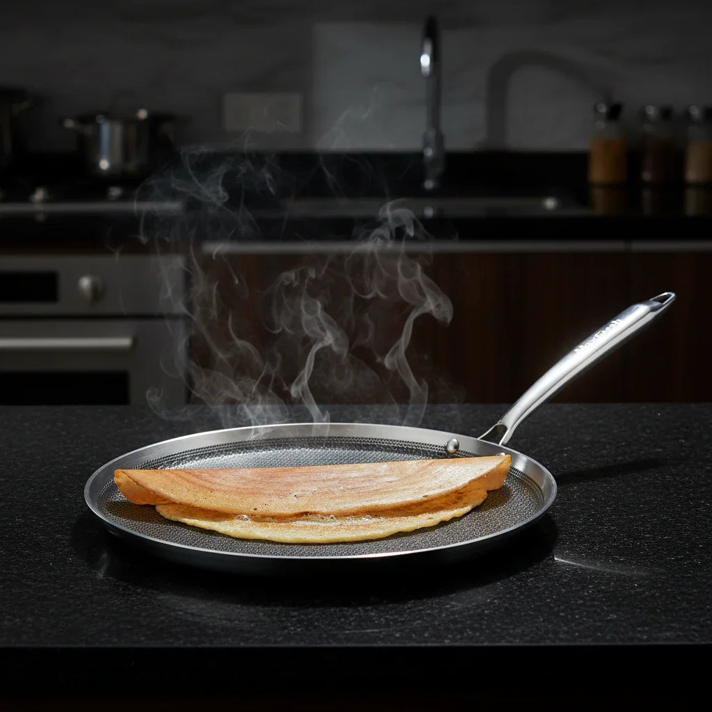 Triply stainless steel dosa tawa with fresh dosa and honeycomb pattern on kitchen counter