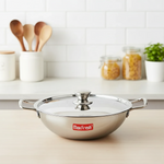 Stainless steel kadai with glass lid and handles on kitchen counter, modern background