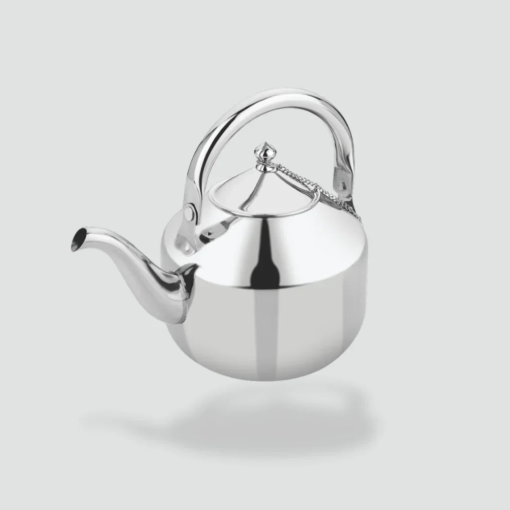 Stainless steel tea kettle with ergonomic handle and attached spout lid on plain background