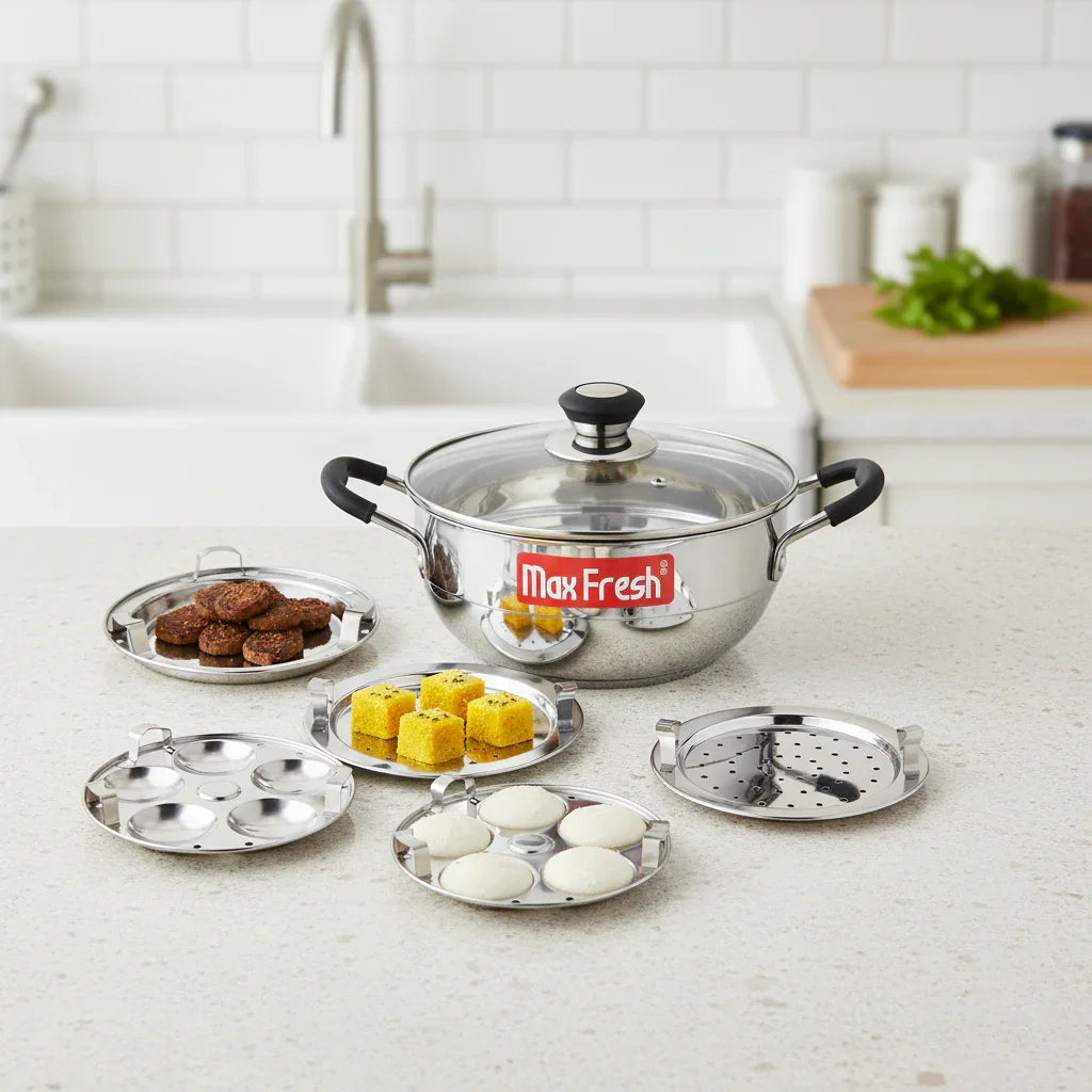 Stainless steel multi kadai with glass lid and 5 cooking plates on a kitchen countertop