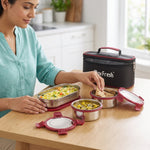 Woman using stainless steel lunch box set with locking lids and insulated carry case on kitchen table