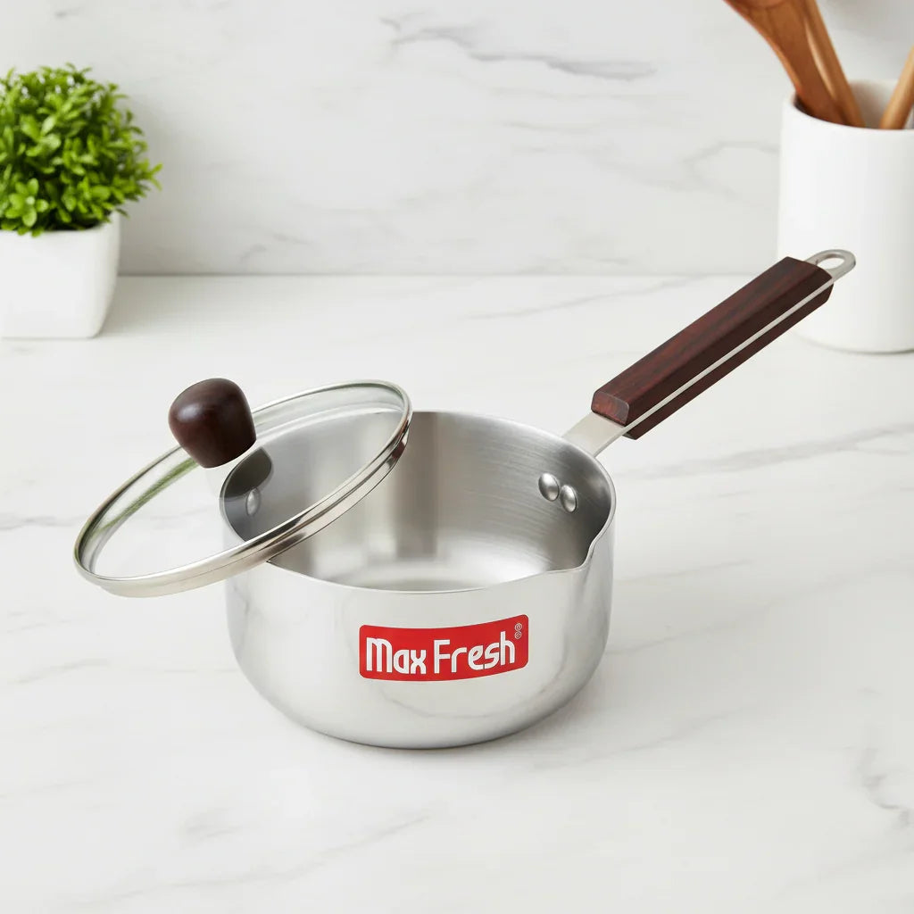 Stainless steel saucepan with glass lid and wooden handle on a kitchen countertop