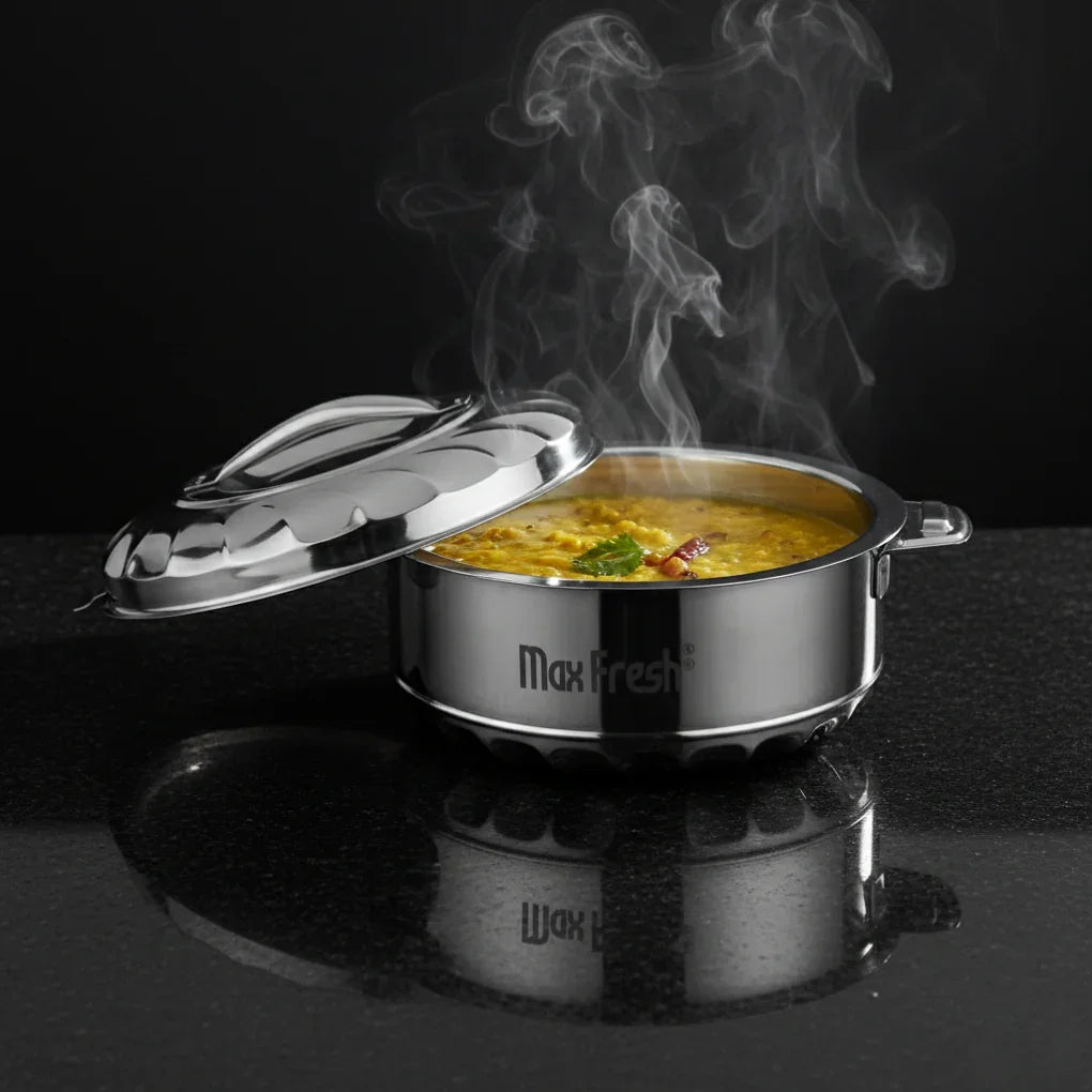 Stainless steel casserole with hot food, steam rising, on a black countertop