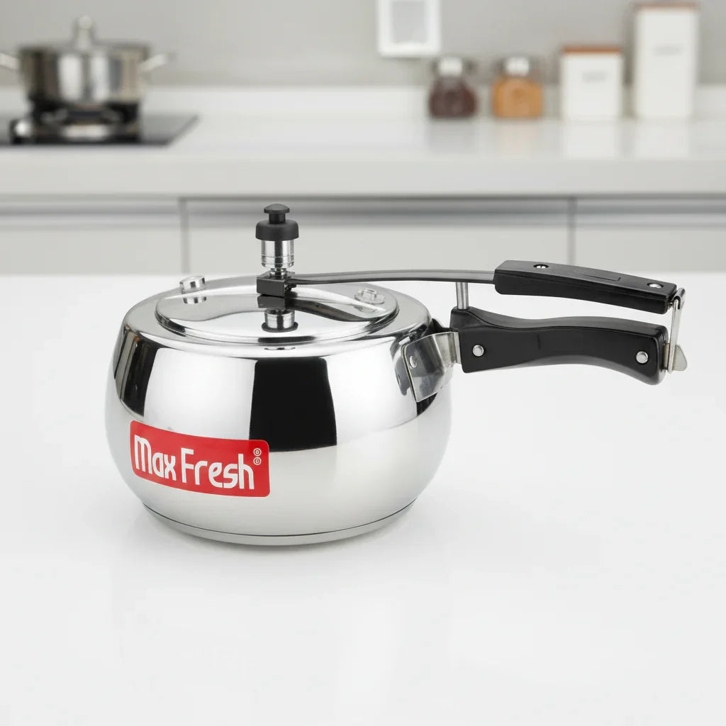 Stainless steel pressure cooker with inner lid and black handles on kitchen counter