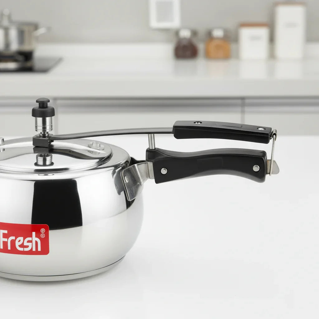 Stainless steel pressure cooker with black handles on a modern kitchen counter