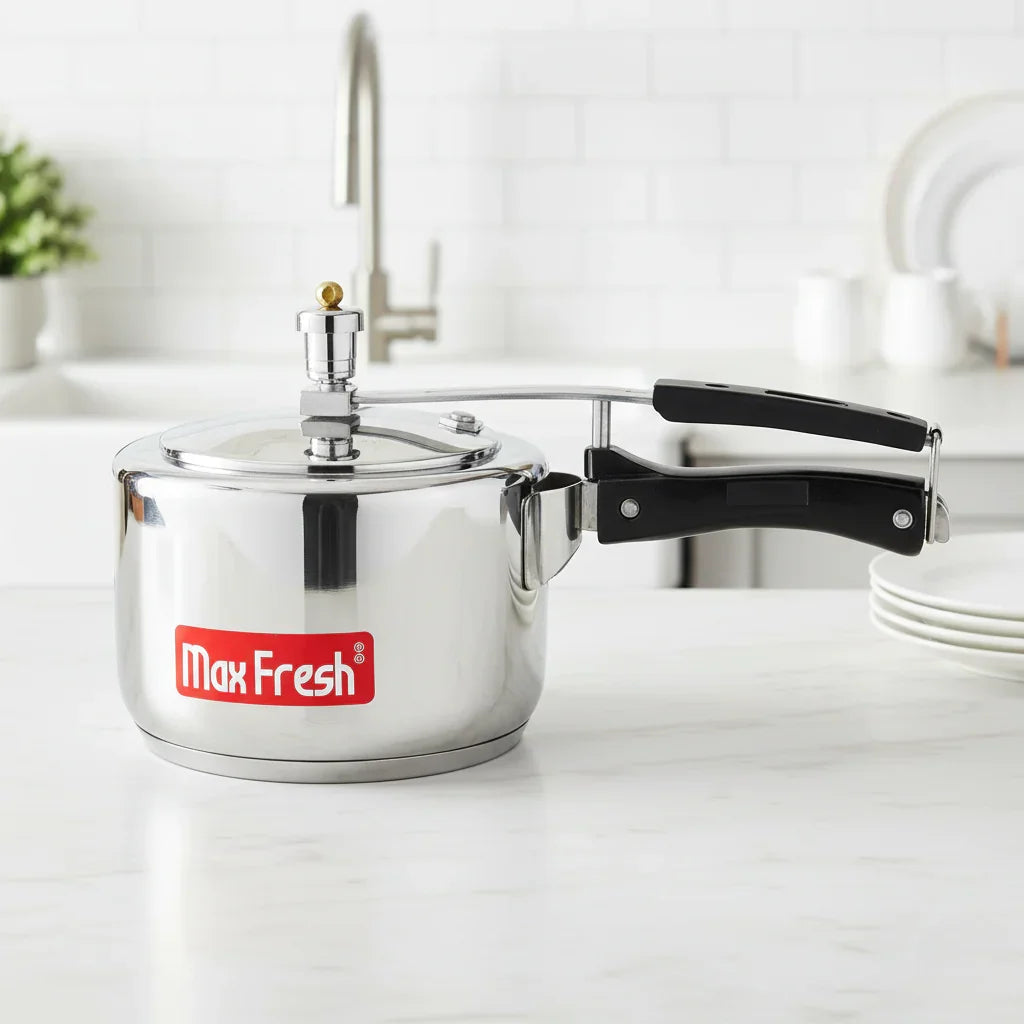 Stainless steel pressure cooker with inner lid and black handles on a kitchen countertop