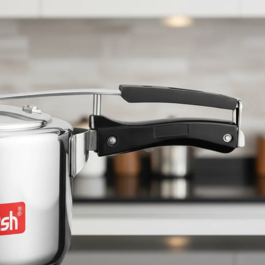 Stainless steel pressure cooker with black handles on a modern kitchen countertop