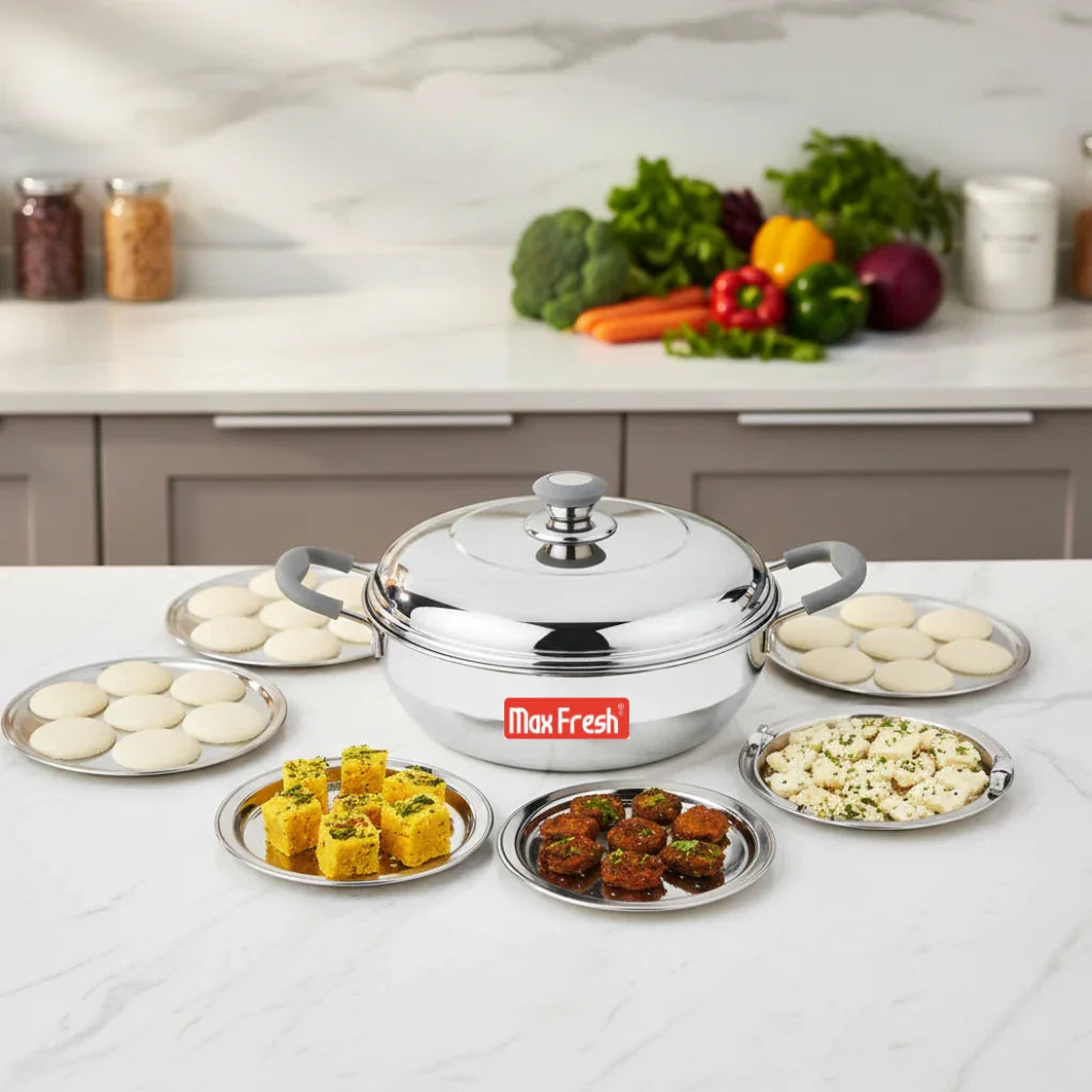 Stainless steel multi kadai with deep base and lid, surrounded by assorted Indian snacks on plates in a modern kitchen.