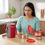 Woman in kitchen with stainless steel lunch box set, insulated bag, and red lids