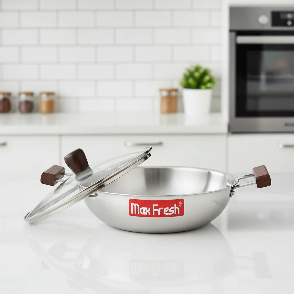 Triply stainless steel kadai with glass lid and wooden handles on kitchen counter