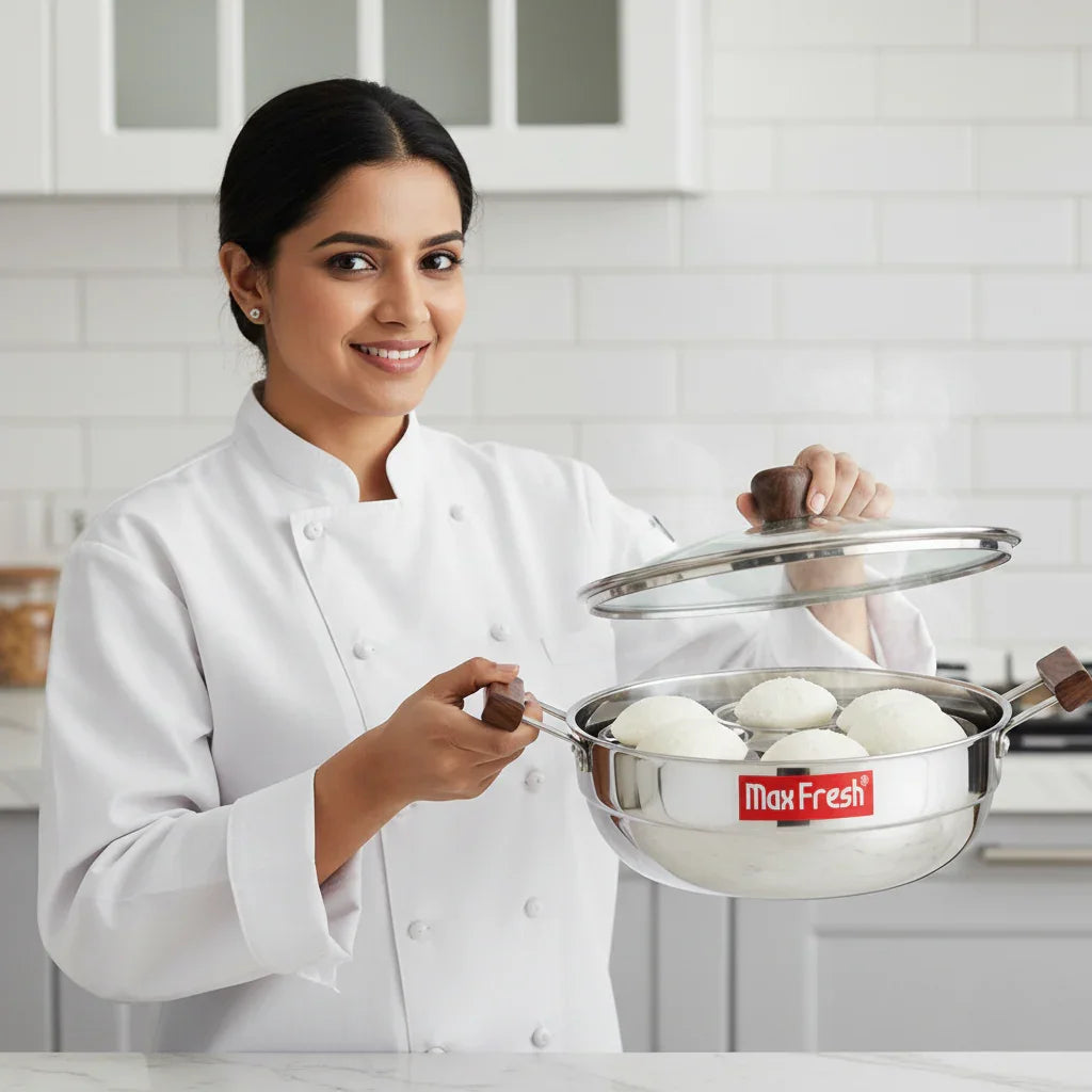 Chef holding stainless steel triply multi kadai with idlis, wooden handles, in modern kitchen