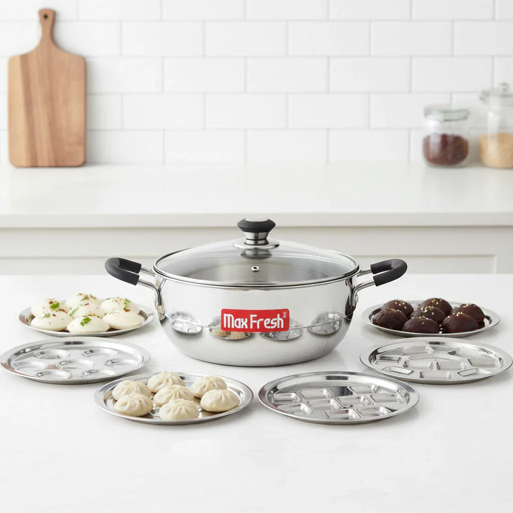 Stainless steel triply multi kadai with glass lid and six steaming plates, displayed on a kitchen counter.