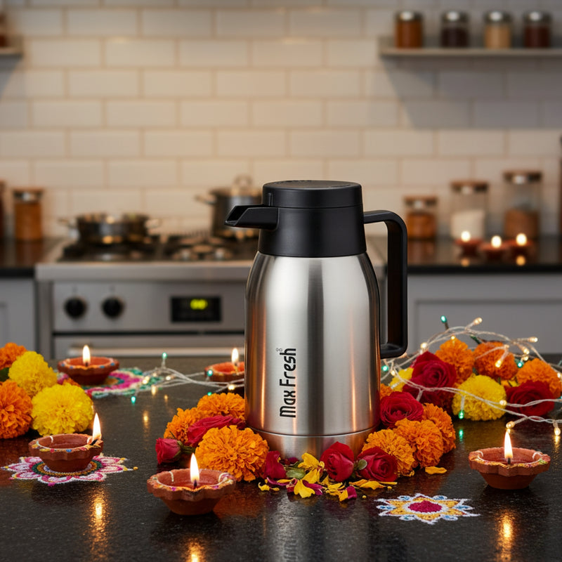 Stainless steel thermos with black lid on a kitchen counter decorated for Diwali.