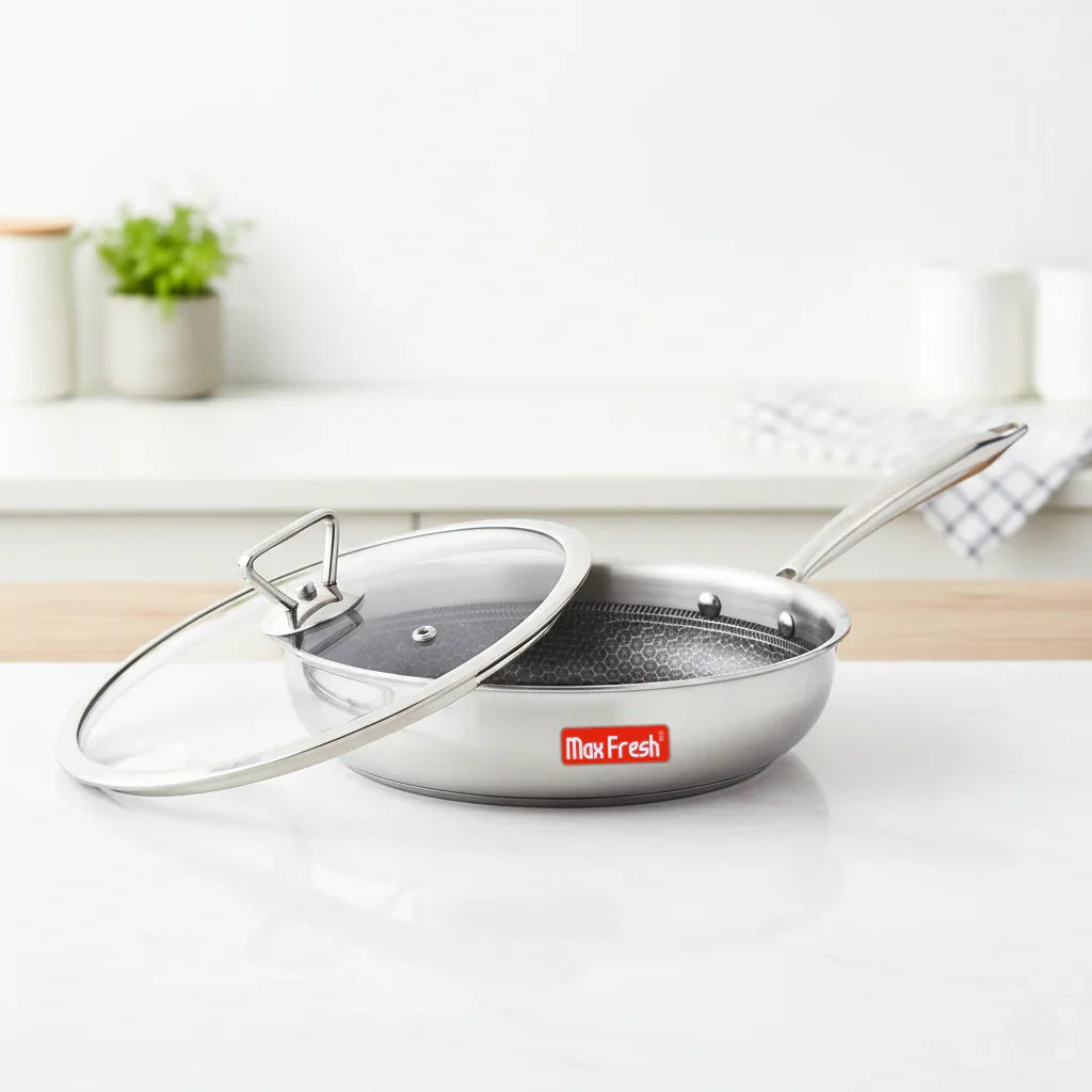 Stainless steel frying pan with honeycomb nonstick surface and glass lid on kitchen counter
