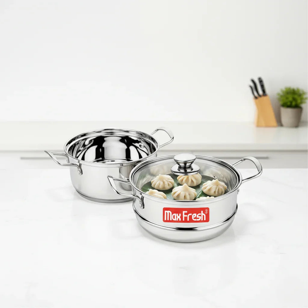 Stainless steel two-tier steamer cookware set with glass lid, featuring steamed dumplings on a kitchen counter.