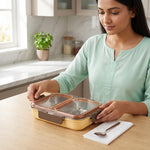 Woman opening a stainless steel lunch box with compartments on a kitchen table